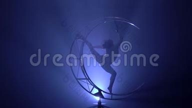 穿着<strong>服装</strong>的体操运动员在黑暗的房间里表演魔术。 蓝色烟雾背景。 慢动作。 <strong>剪影</strong>